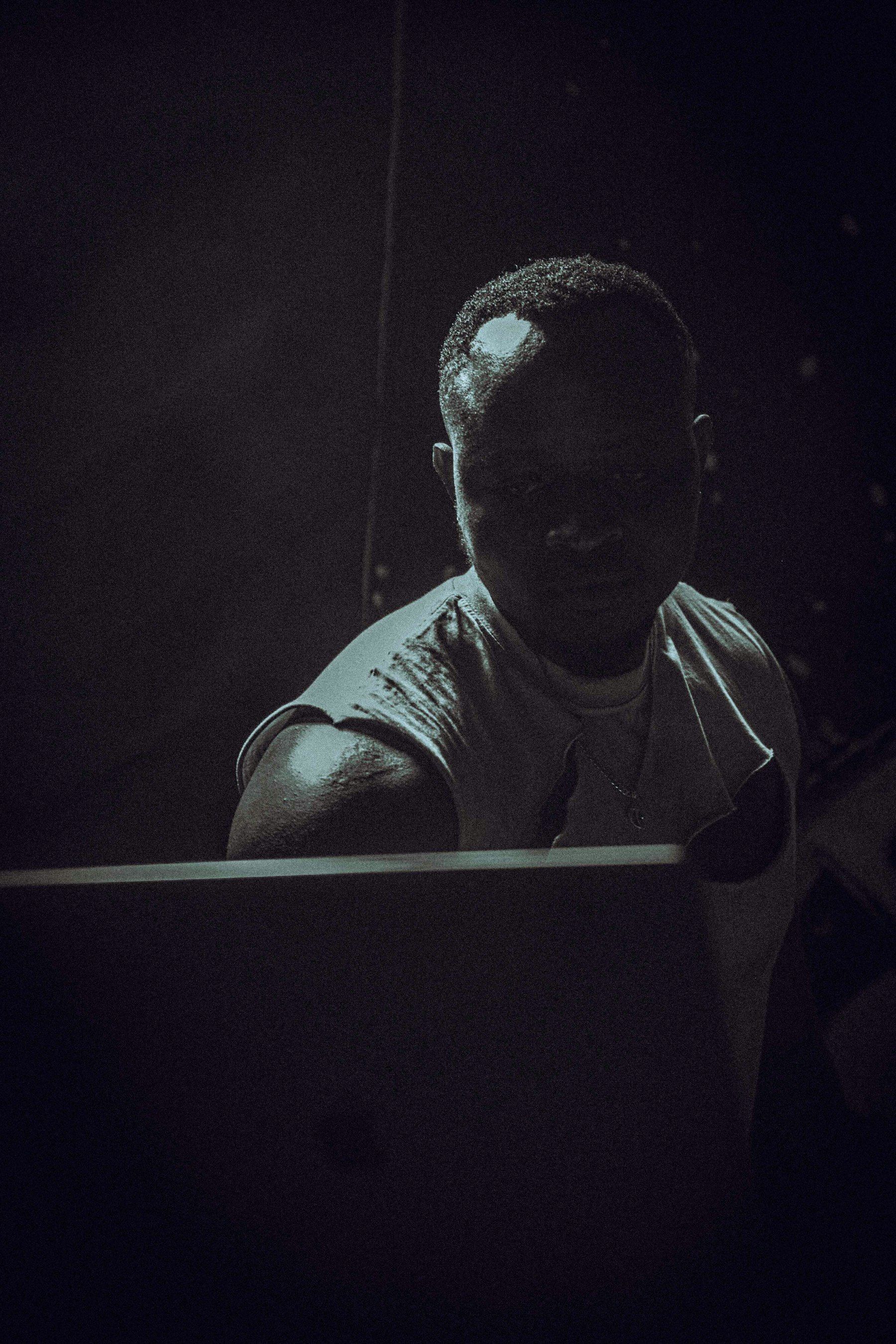 A man in a dark room, lit by the screen in front of him.